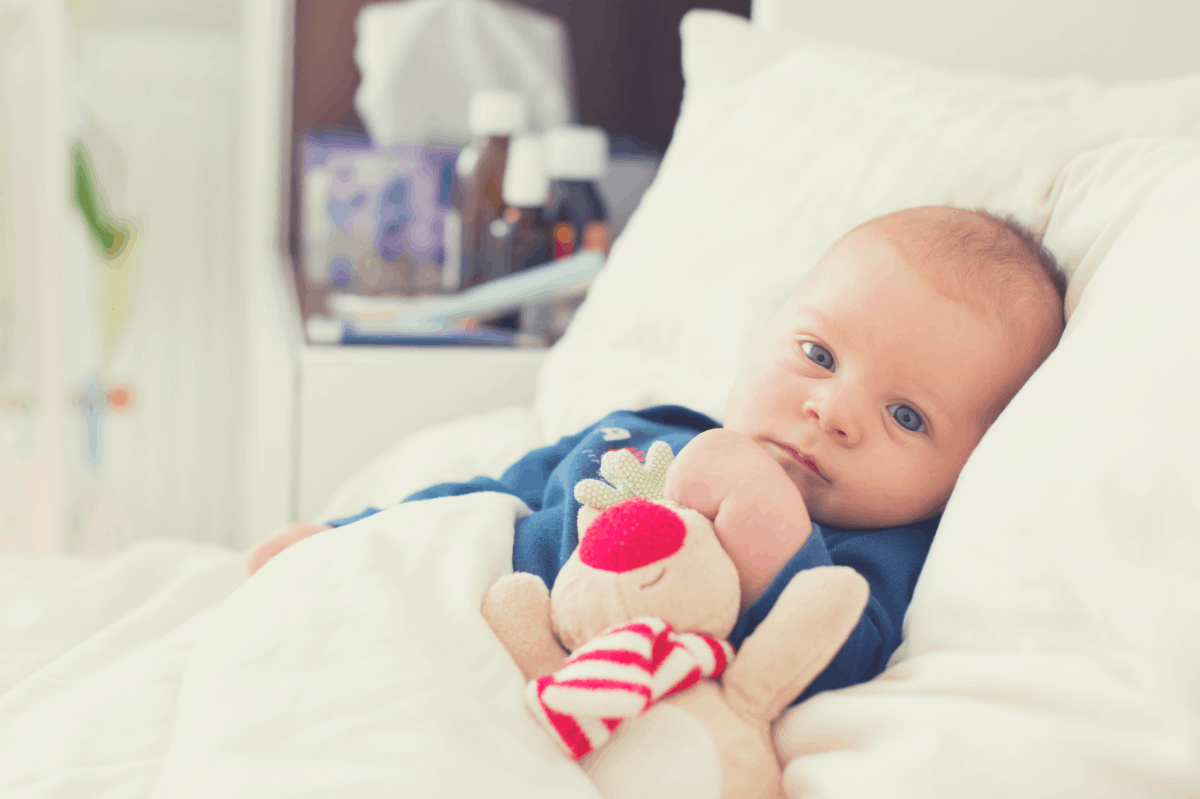 newborn lying on his back with head resting on a pillow