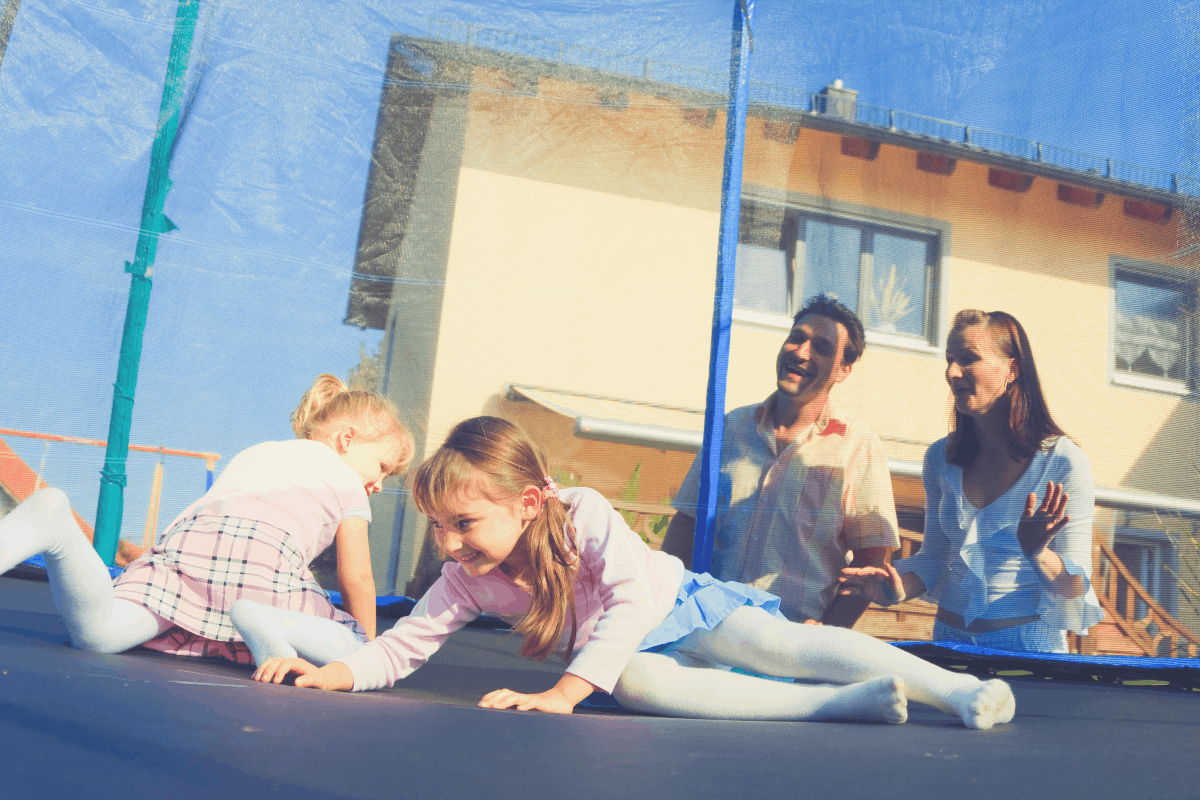 parents watching their daughters playing on a trampoline