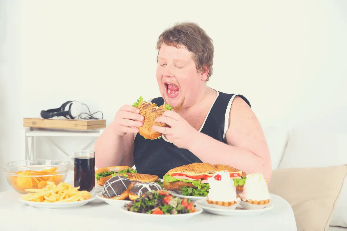overweight man eating several plates of food