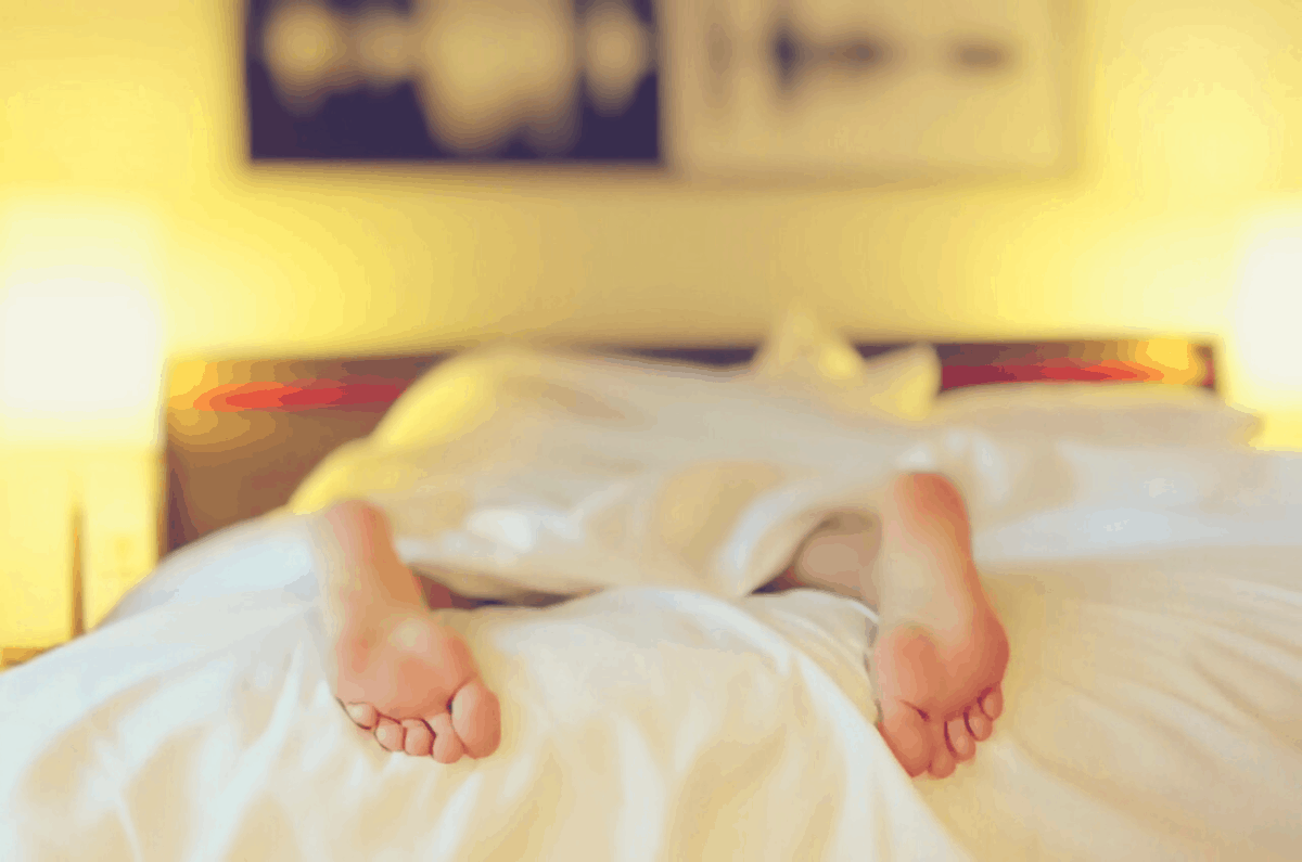 sleeper lying down in a bed with white bed sheets