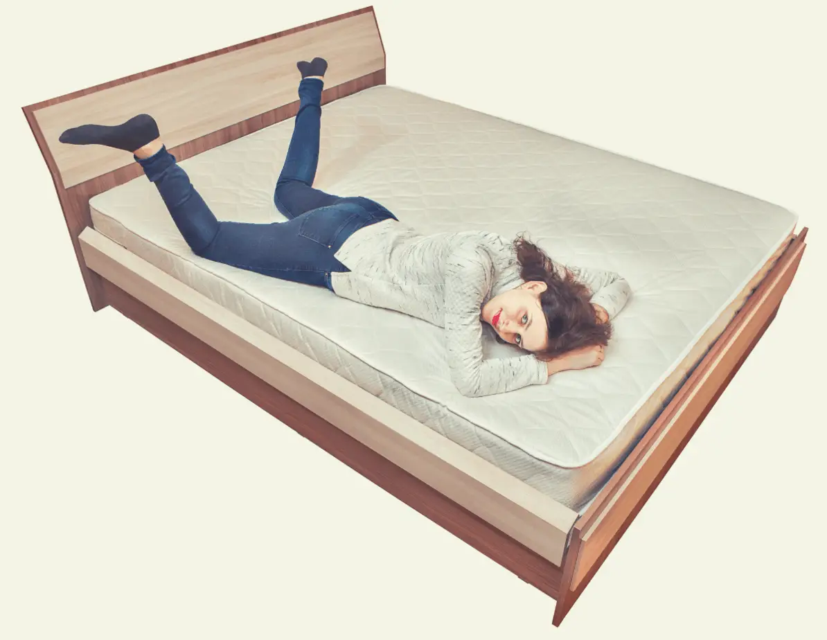 caucasian woman lying down on an innerspring mattress on laid on a wooden bed