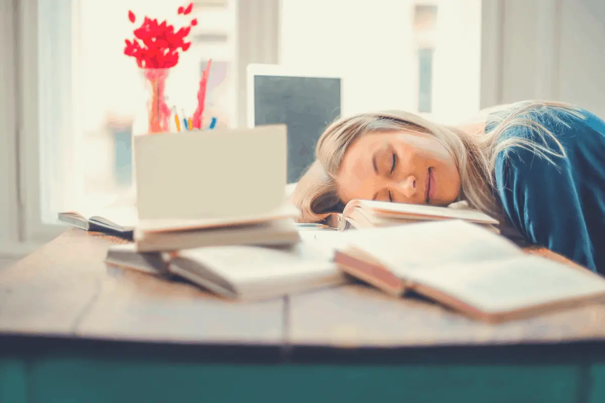 blonde woman taking a power nap on a desk after reading