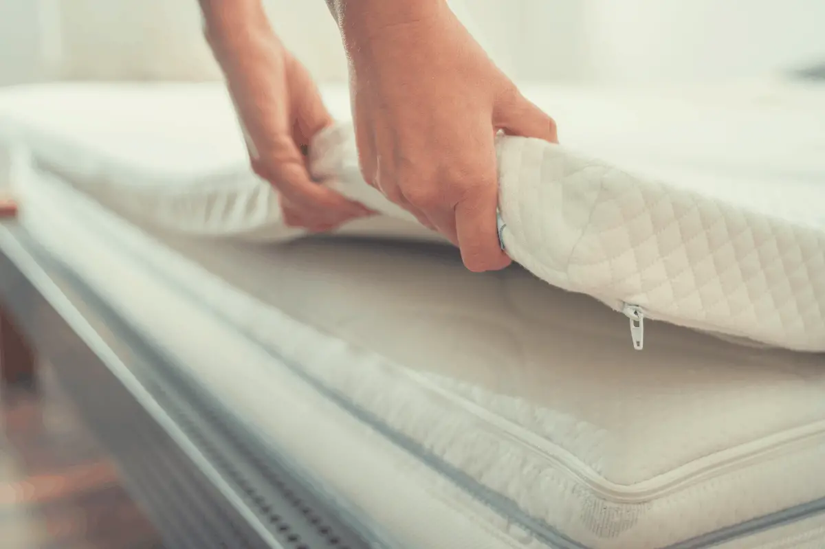 mattress topper being laid on a regular mattress