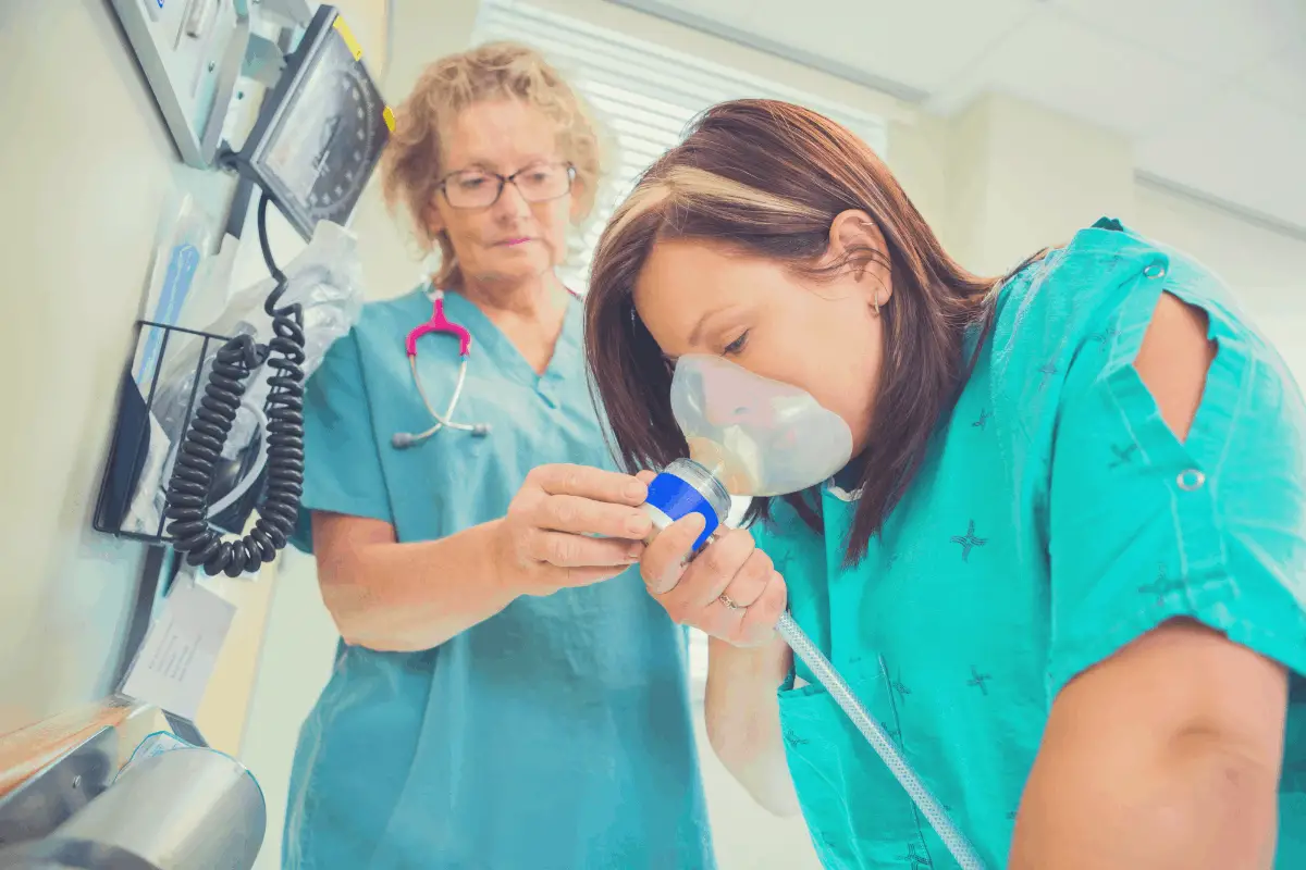 woman inhaling laughing gas under supervision by a doctor