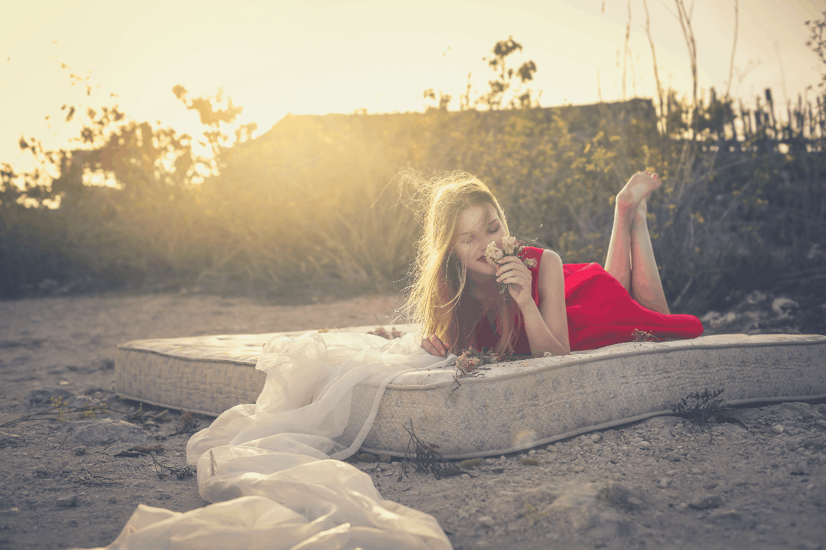 blonde woman lying down on a mattress in the sun