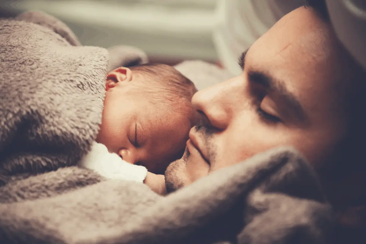 man sleeping with newborn baby