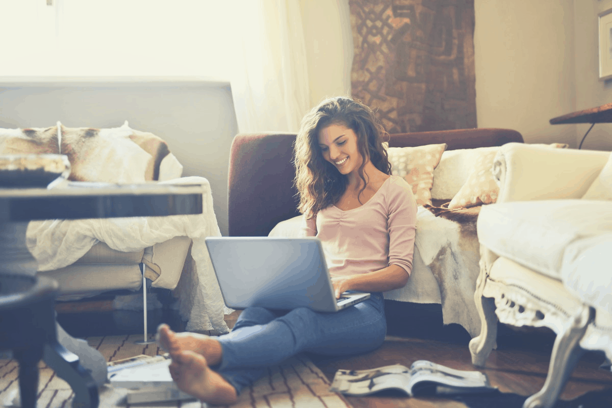 smiling brunette working on her laptop in the bedroom