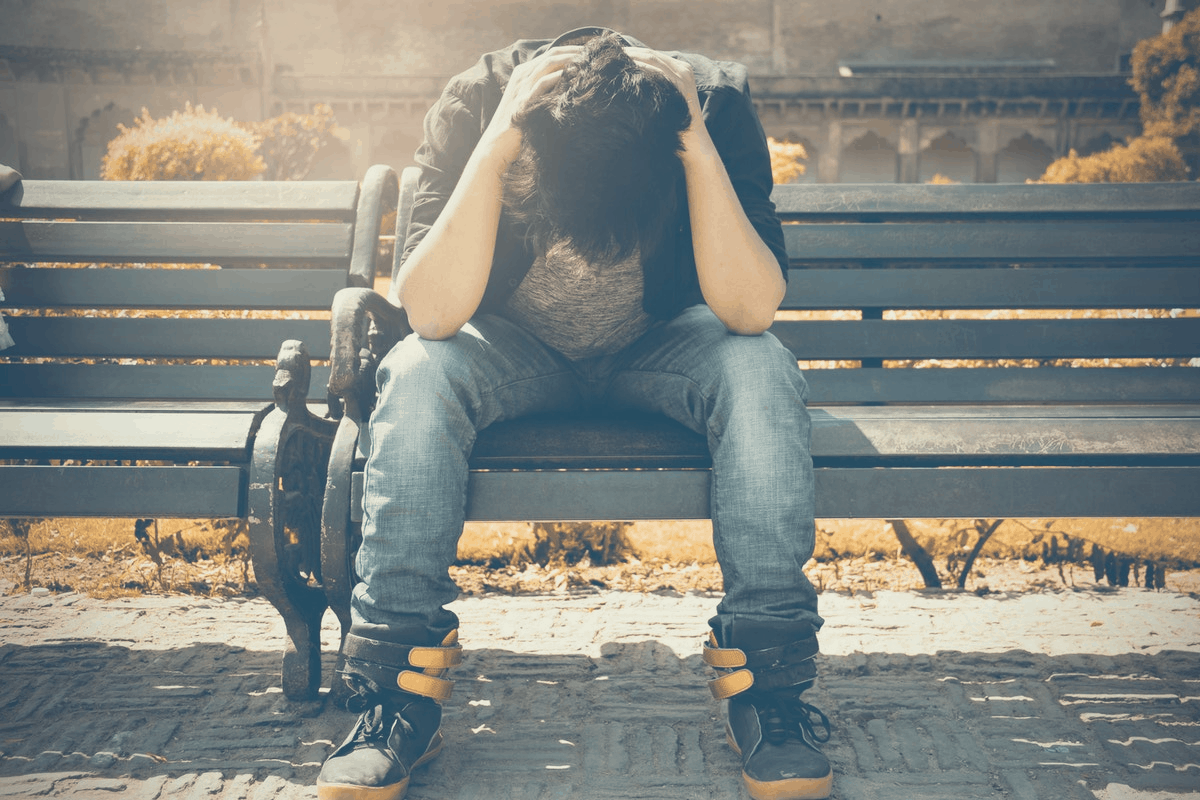 depressed man sitting on a park bench