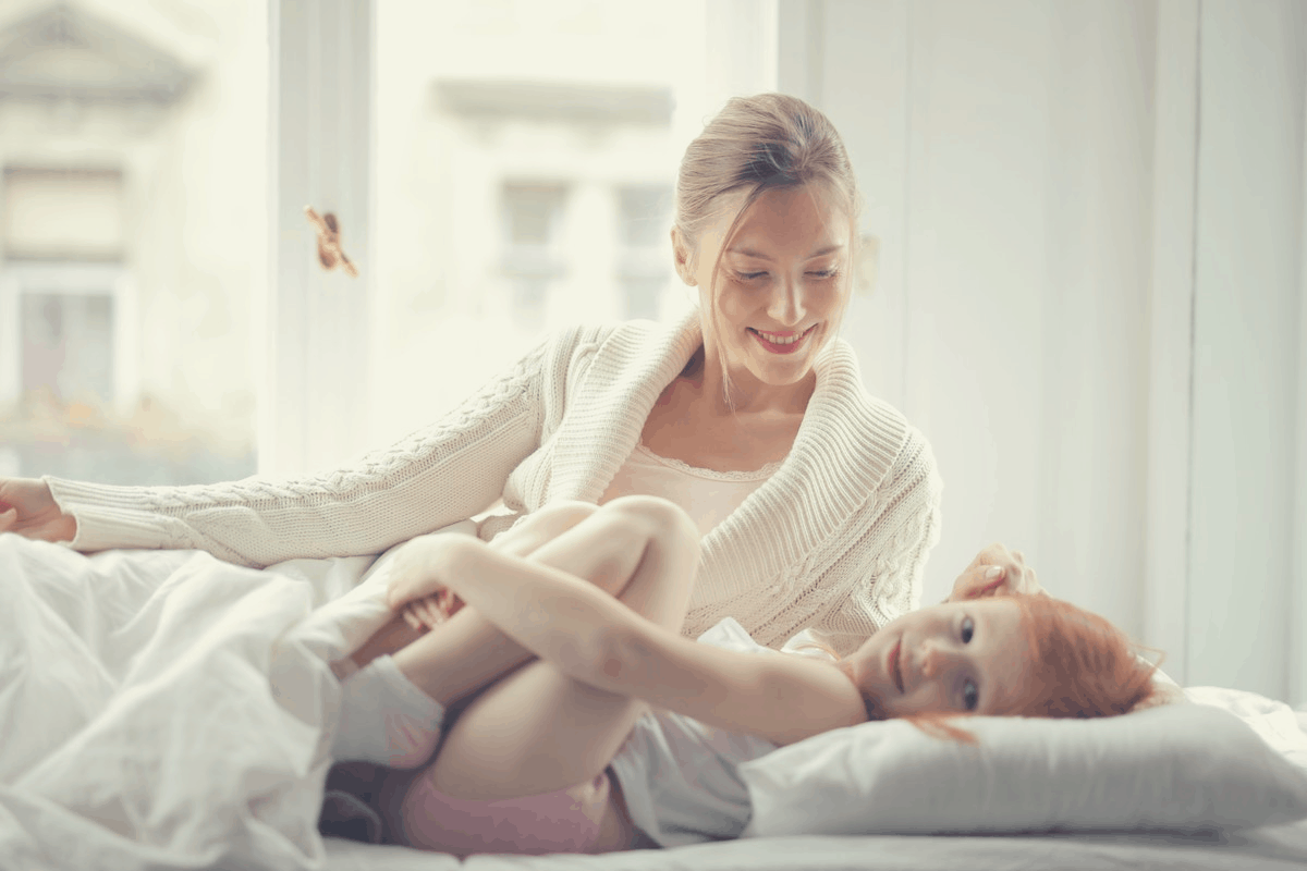 woman and daughter lying in bed wearing loose clothes