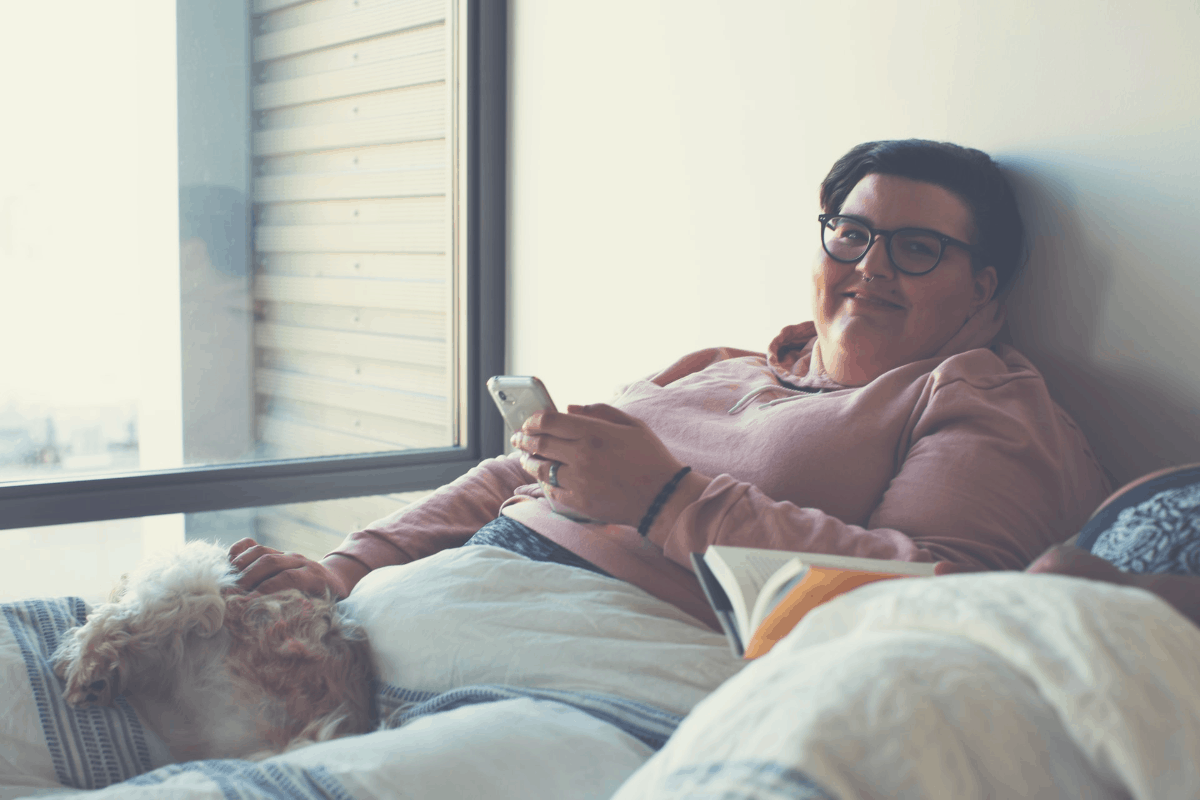 man in glasses sharing a bed with a pet dog