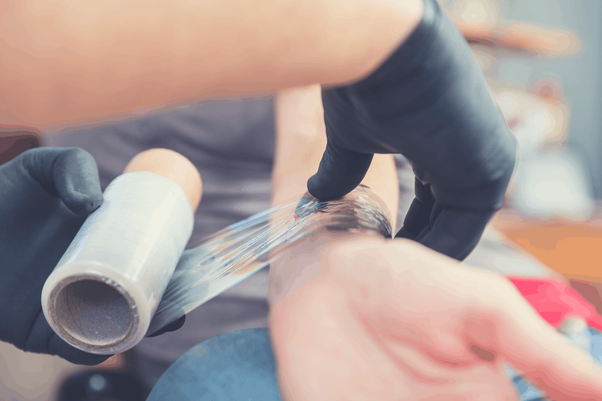 tattoo artist wrapping a new tattoo