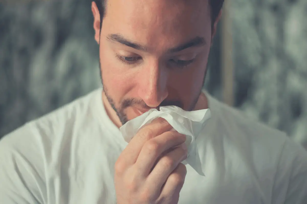 man using a tissue to clean a dripping nose