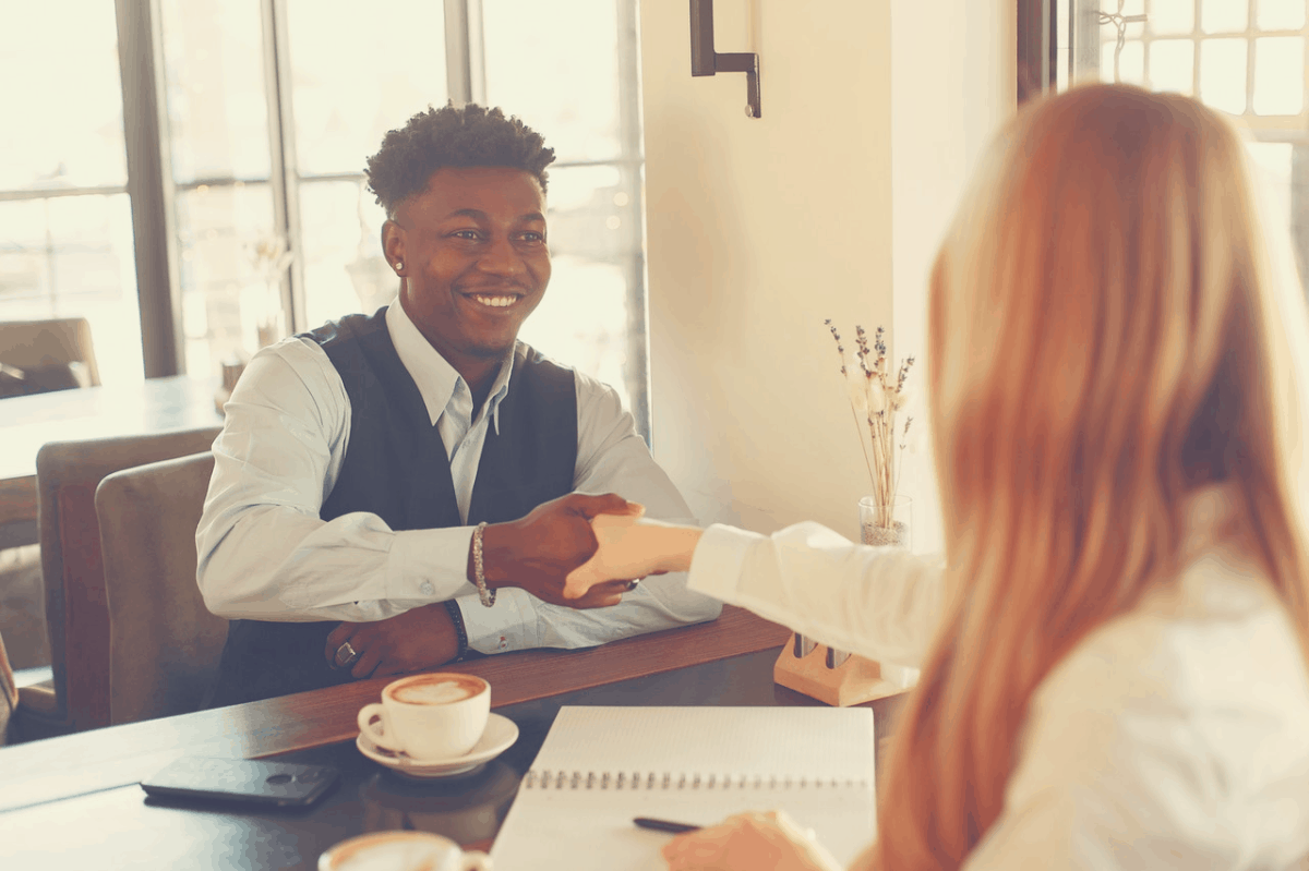 man and woman shaking hands over coffee