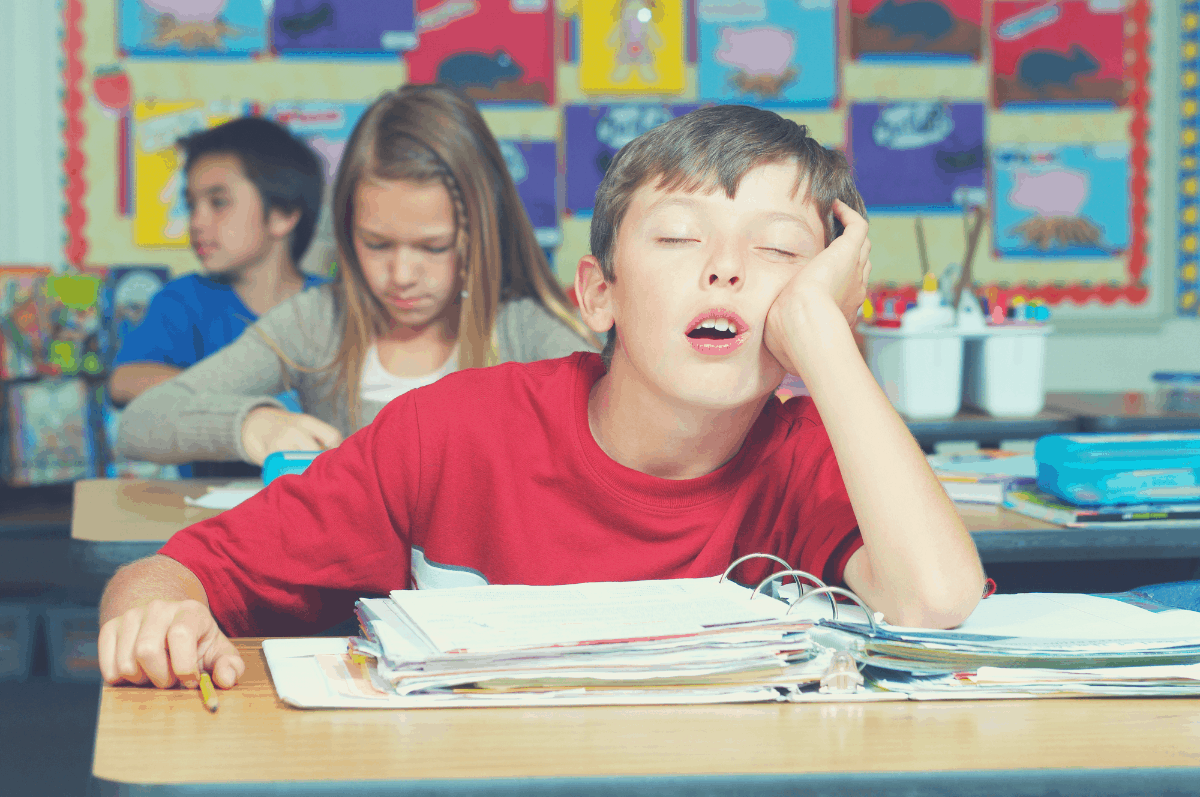 boy sleeping in class with an elbow propping the head