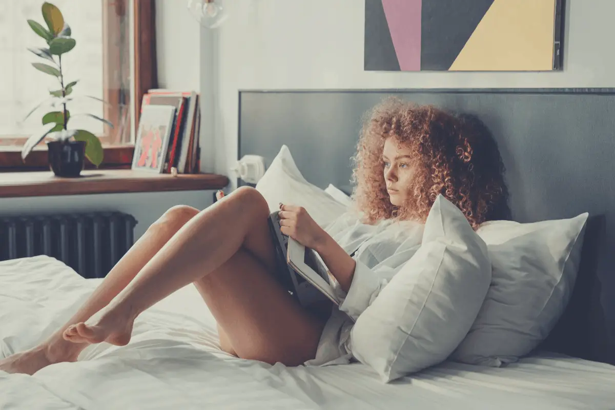 curly haired woman reading in bed