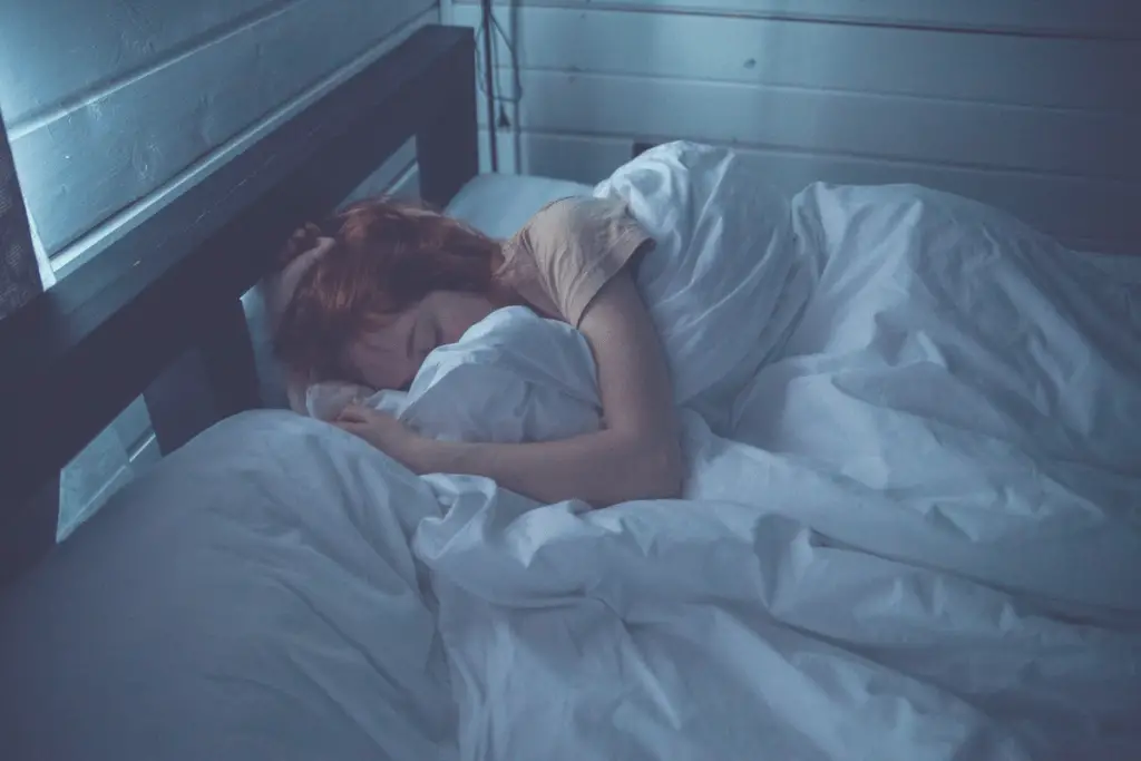 redhead sleeping in a bed with a pillow and white sheets