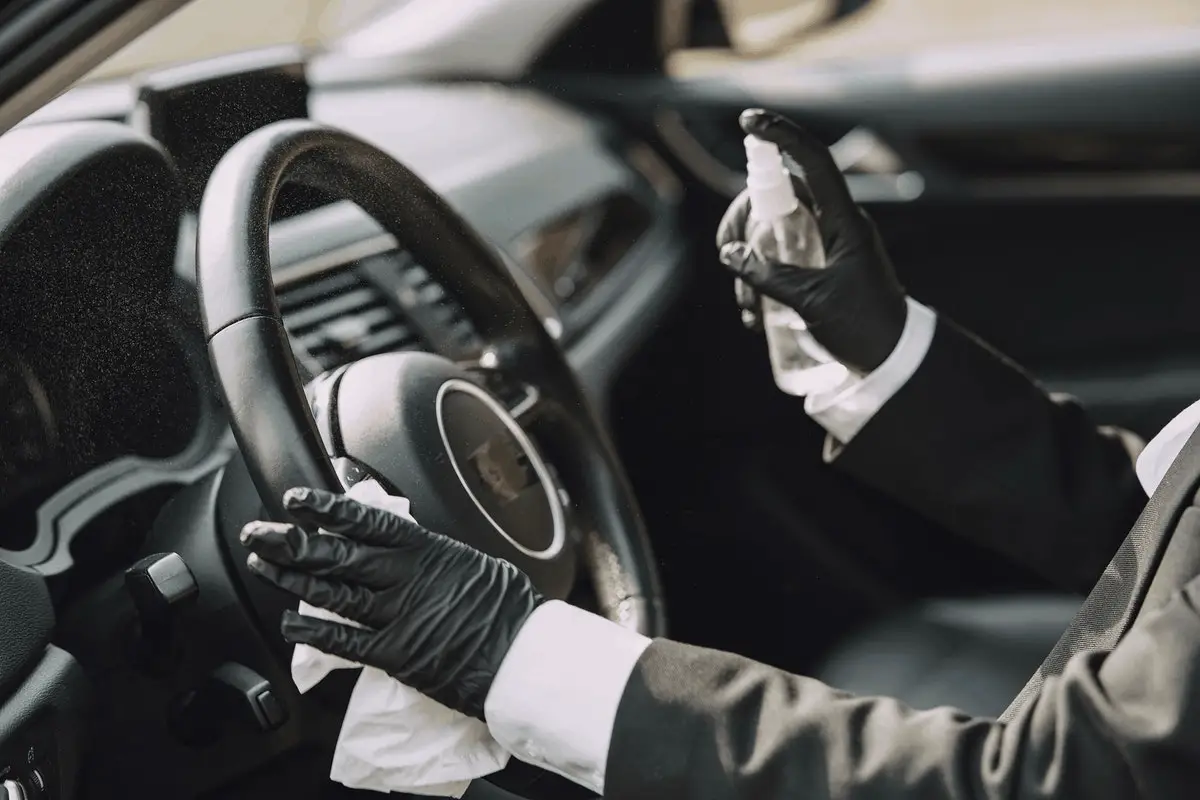 person in gloves and protective gear spraying the interiors of a car
